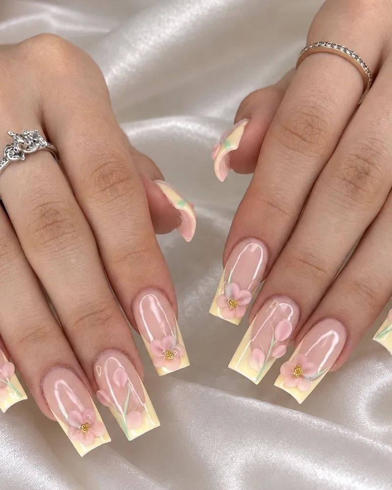 Square nails with pale yellow French tips and 3D pink flowers at Chillux Nails, Orpington